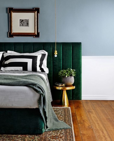 an emerald velvet padded headboard and brass accents that make the color stand out even more