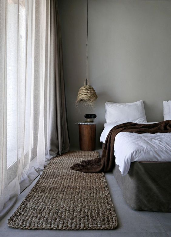 a bedroom with much texture - jute, wicker, various textiles and concrete walls and floors