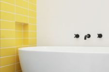 24 a minimalist bathroom with a statement yellow tile wall and a neutral and sleek bathtub