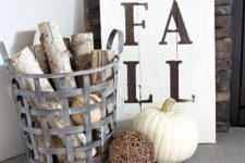 26 a metal basket with branches, a plaid blanket, a vine ball, a white pumpkin and a sign