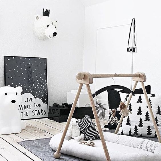 a Nordic nursery with a baby gym, artworks, a rug and toy bear heads to make it more atmospheric
