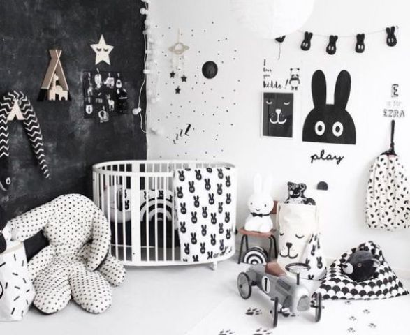 a catchy and bold nurseyr with a black wall, some prints, a gallery wall of artworks and garlands and lot sof toys