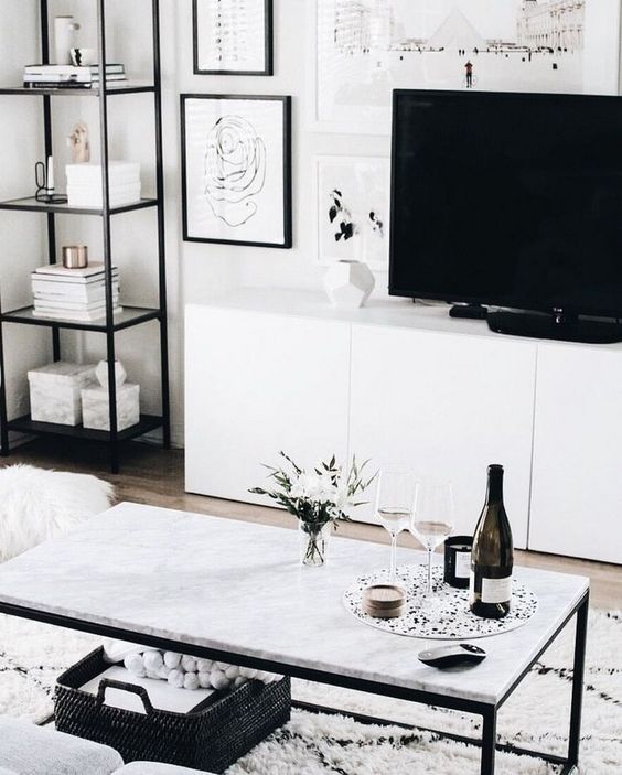 a chic Nordic living room with white furniture, some touches of black and a gallery wall, prints are incorporated with a rug