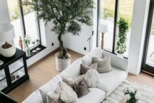 a chic black and white living room diluted with some natural wood and a crochet rug plus greenery for a welcoming feel
