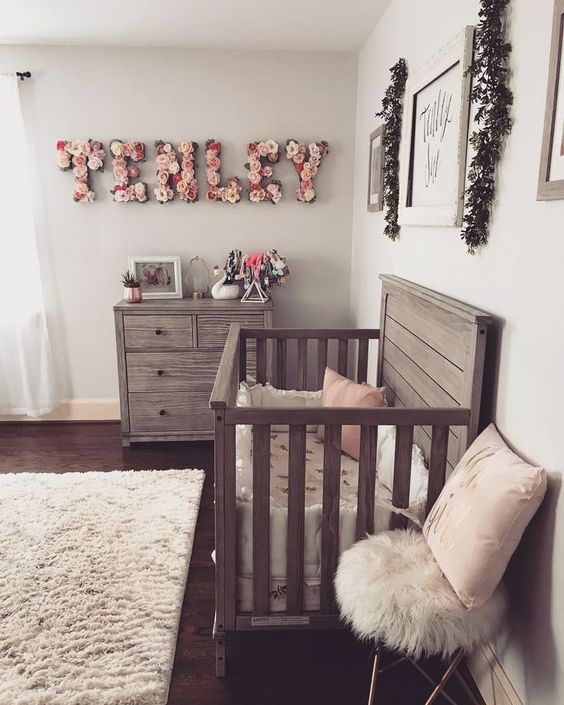a chic farmhouse meets vintage and boho nursery with reclaimed wooden furniture, a floral name, fluffy rugs and artworks