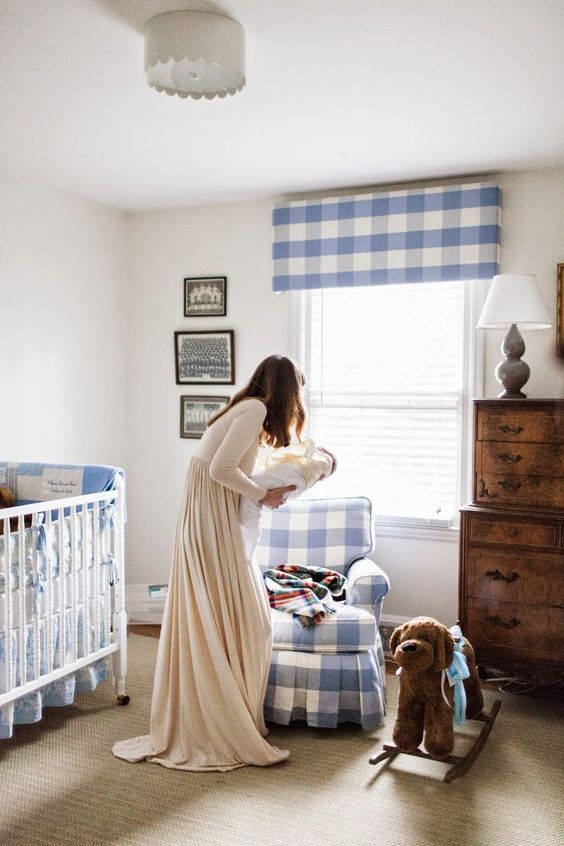 a cute famrhouse nursery with lot sof blue plaid, a stained dresser, a neutral rug and a white vintage crib