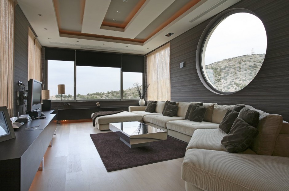 a gorgeous contemporary living room with a large round window and a panoramic window with shades to maximize the views