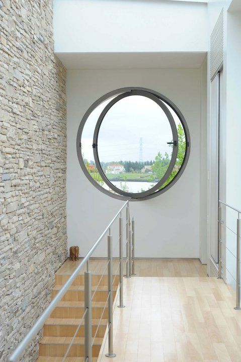 a modern porthole window in the staircase space is a cool way to add light and create an illusion of more space