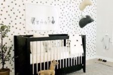 a monochromatic space with a printed wall, a black crib, toy heads on the wall and a large rug