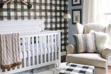 a welcoming farmhouse nursery with a plaid statement wall and a matching ottoman, neutral furniture and a unique sphere chandelier