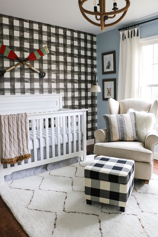 a welcoming farmhouse nursery with a plaid statement wall and a matching ottoman, neutral furniture and a unique sphere chandelier