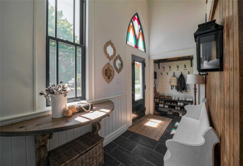 The entryway is done with much natural wood, dark tiles, and white wood cladding all the walls