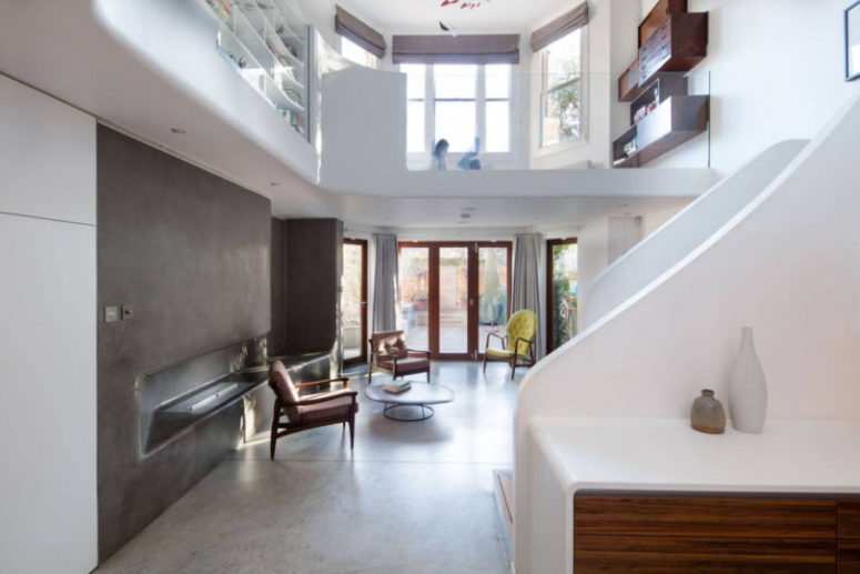 The living room is surprisingly decorated with concrete, which covers the floor and the wall, there's a glazed wall, too, which brings much light inside