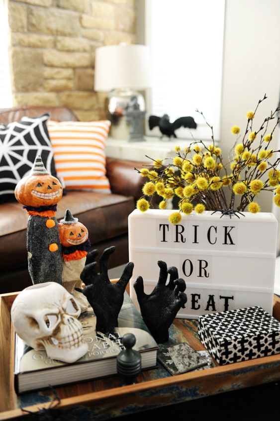 a coffee table styled with a Trick or Treat sign, billy balls, fake hands and a skull plus spooky figurines with pumpkin heads
