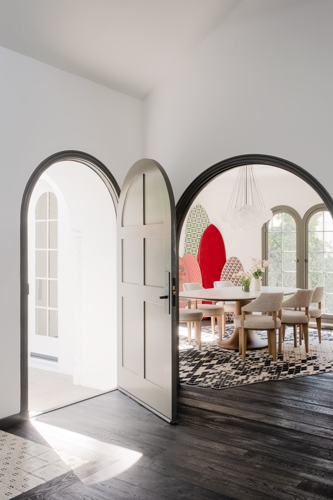 The dining space is accentuated with a printed rug, bold surf boards and a cluster of pendant lamps