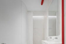 06 The bathroom is white and minimalist, with touches of red, an oval tub and a marble floating vanity