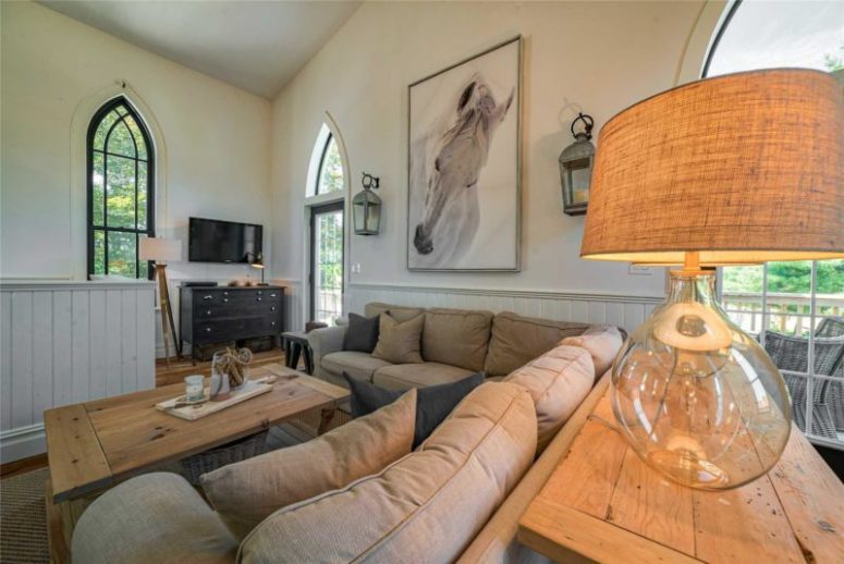 The living room is done with a corner sofa, lamps, a wooden table and a TV on the wall