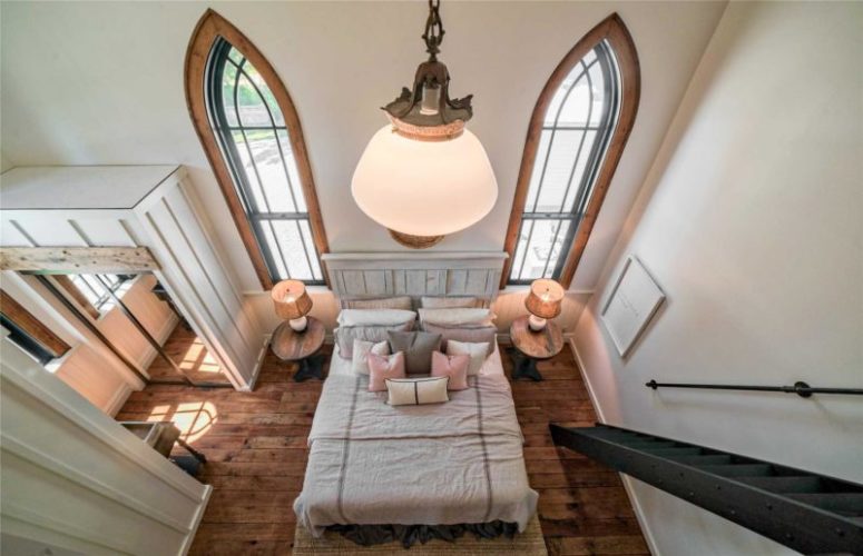 The bedorom is done with wooden floors, a comfy bed, a couple of nightstands and lamps