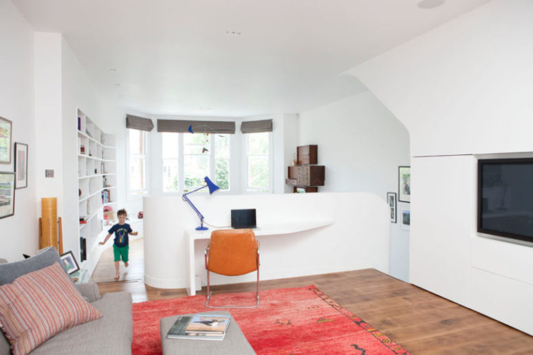 The living room zone on the upper floor features some colorful accents and a home office nook with a desk built in right into the railing The living room zone on the upper floor features some colorful accents and a home office nook with a desk built in right into the railing