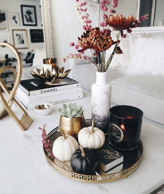 a stylish fall arrangement of a tray with blakc and white embellished pumpkins, a black candleholder and dried blooms in an ombre vase