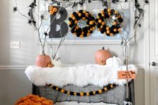 09 a Halloween entryway console with a printed rug, a bold floral arrangement, pompom wreaths, branches with spiders and witches’ hats