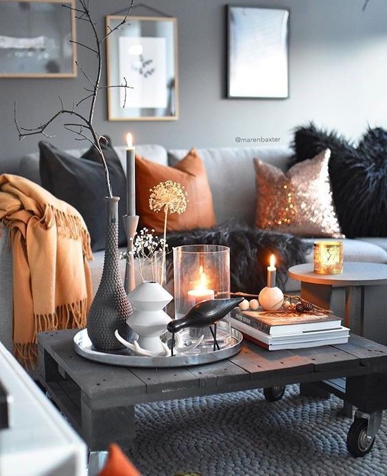 minimalist Halloween coffee table decor with candles, grey and white vases with branches and dried blooms, a faux blackbird