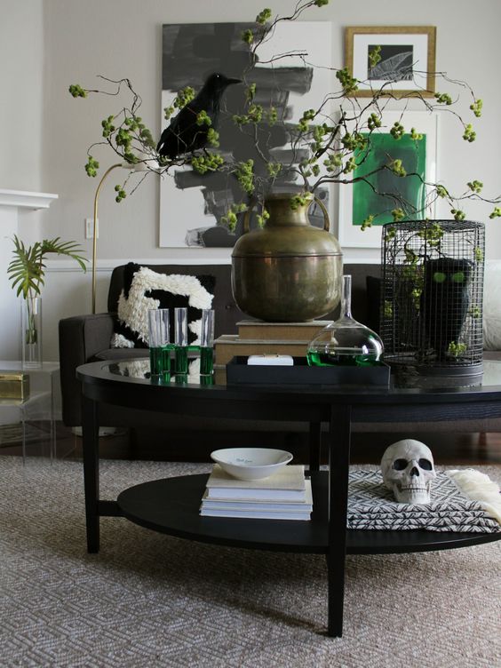 pretty Halloween coffee table styling with a skull, an owl in a cage and some greenery branches with a blackbird