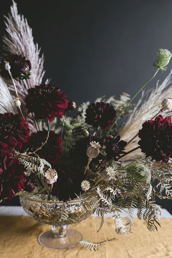 a super elegant Halloween centerpiece of a silver bowl and moody florals plus white dried herbs and greenery
