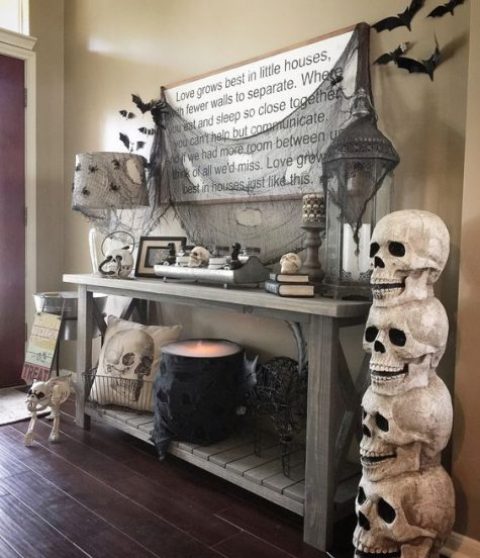 a rustic console with black bats and spiders, black spiderweb and a lit up cauldron plus skulls