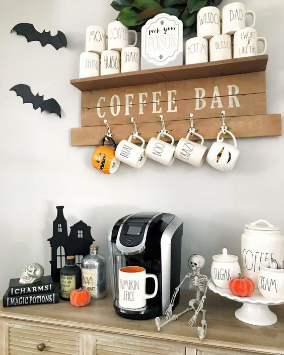 a Halloween coffee bar decorated with bats, skeletons, Halloween mugs and some skulls and pumpkins