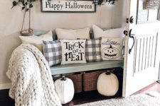 18 a farmhouse entryway dressed up for Halloween with Halloween pillows, a sign and some dark greenery
