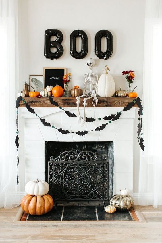 a chic and fun Halloween mantel with a skeleton, painted pumpkins, a black bat bunting, black balloon letters and a stylish sign