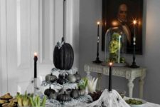 22 a creative Halloween centerpiece of a stand with glitter silver and black pumpkins plus pale greenery