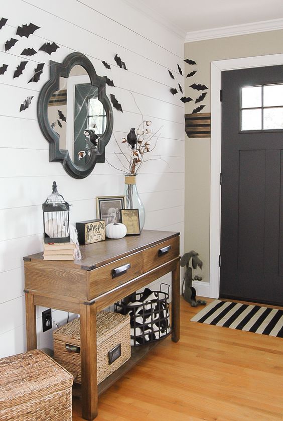 a simple farmhouse Halloween entryway with bats, black and white touches, blackbirds and some white pumpkins