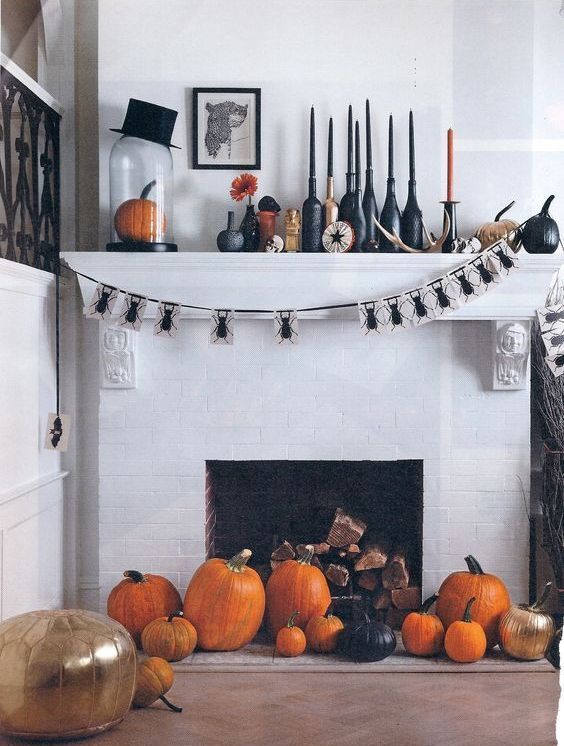 a bold Halloween mantel with black and orange candles, black candleholders, black and orange pumpkins, a spider bunting