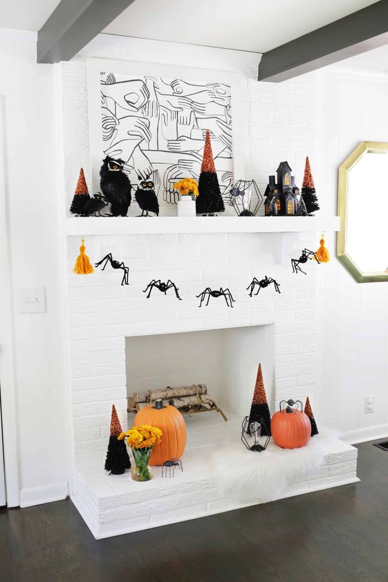 a bright Halloween mantel with orange pumpkins, bold black and orange trees, a cage candleholder