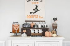 26 a chic farmhouse Halloween drink station with a sign, fabric pumpkins, witches’ brew and some cat toppers