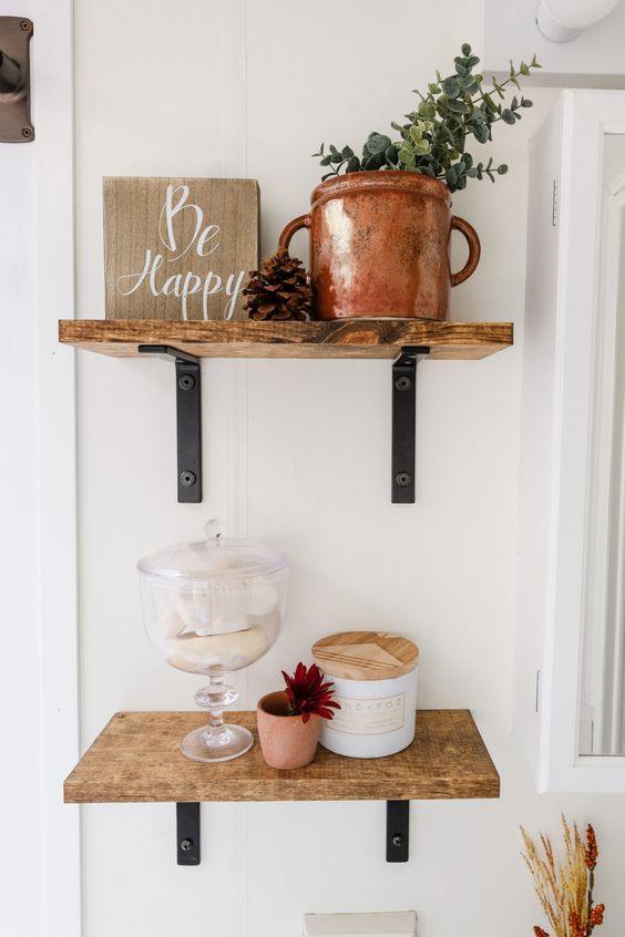 wooden shelves, a sign, a copper pot with eucalyptus, some soaps in a jar and a bloom make up a pretty fall arrangement