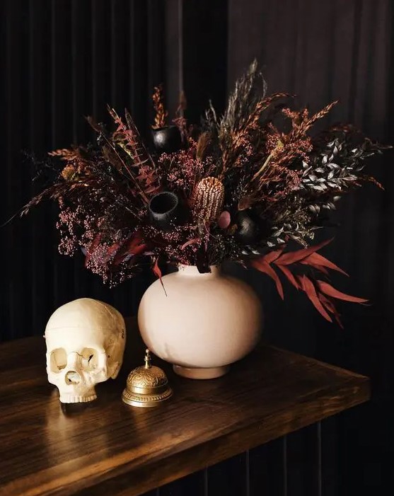 a beautiful and moody Halloween wedding centerpiece of dark and burgundy grasses, foliage and some seed pods looks jaw-dropping