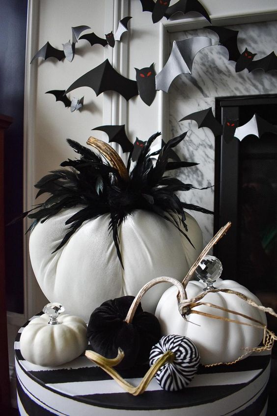 a black and white Halloween centerpiece of fabric pumpkins and feathers is a cool and long-lasting idea