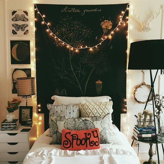 a black tapestry, lights, black lamps, moon phase artworks and a fun pillow add Halloween flavor to the bedroom