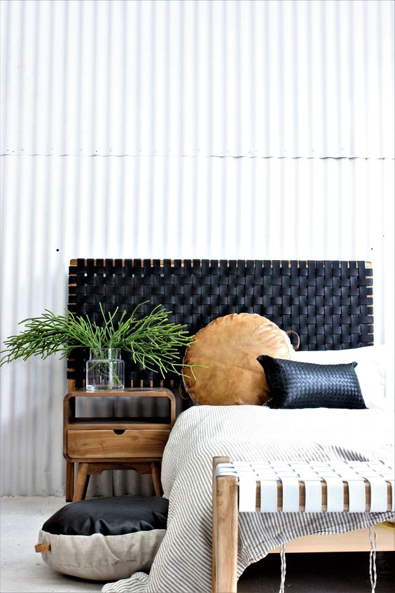 a boho bedroom with a bed and a leather woven headboard, with leather pillows, a nightstand and a woven bench