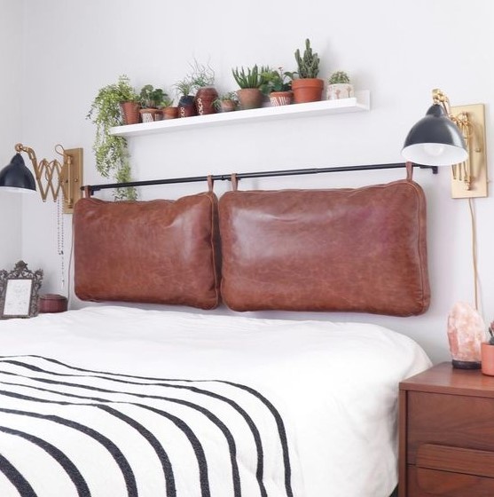 a contemporary meets boho bedroom with a brown leather pillow headboard on a black holder