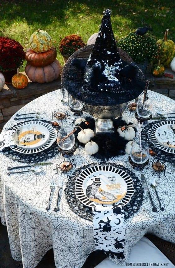 a creative Halloween centerpiece of a bowl with a witch hat and some pumpkins around