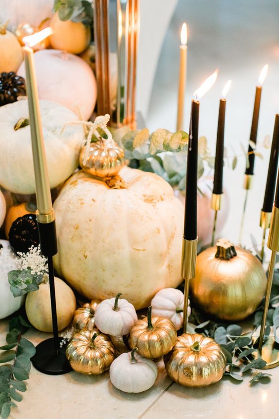 a refined Halloween centerpiece of white and gold pumpkins, black and gold candleholders with matching candles