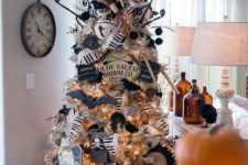 a silver Halloween tree decorated with a witch hat and brooms, with banners, garlands, bats and skulls