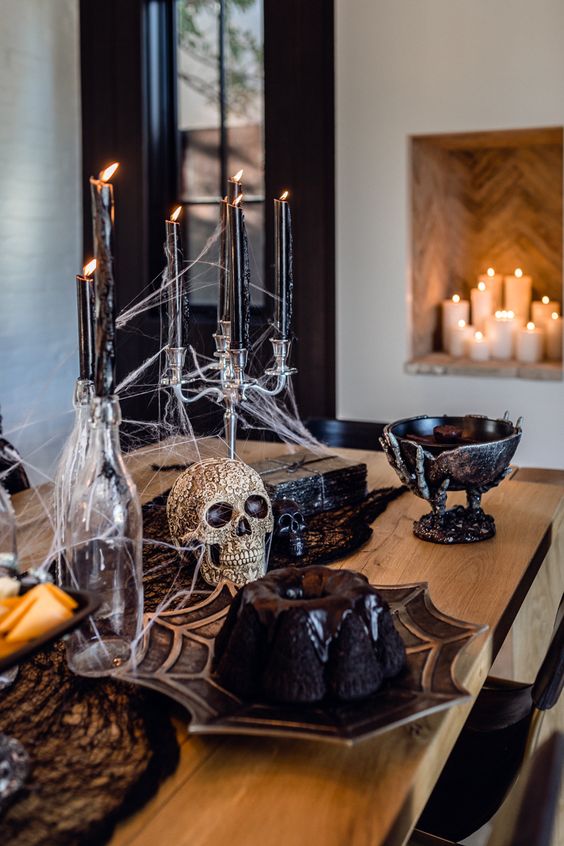 a simple Halloween centerpiece of an embellished skull, a candelabra with black candles, spiderweb