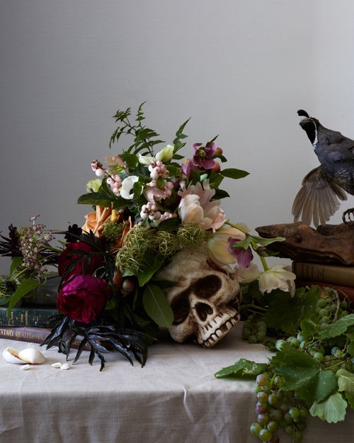 a skull, a faux bird and some moody blooms and greenery are a gorgeous idea of a Halloween centerpiece