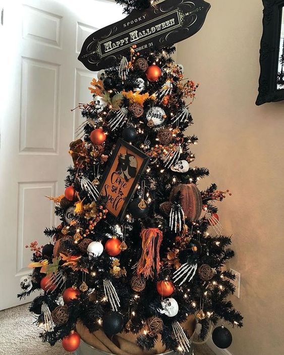 a spooky black Halloween tree decorated with skeleton hands, pumpkins, black and orange ornaments, a sign and lights