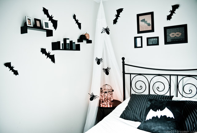 a stylish black and white Halloween bedroom spruced up with bats, spiders, a light cage and soem artworks on the wall